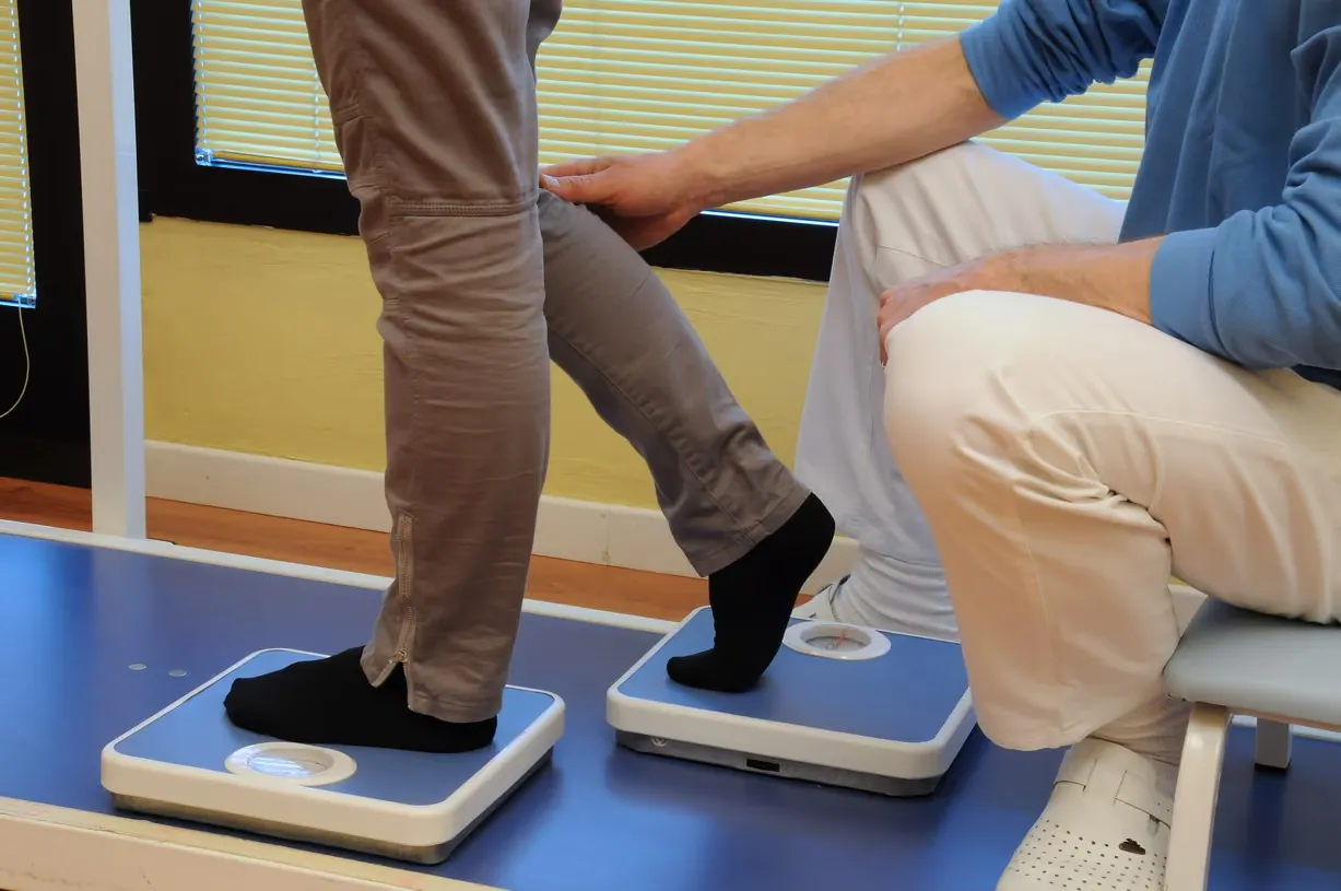 Una persona fa esercizi di fisioterapia con un terapista che sostiene la sua gamba.